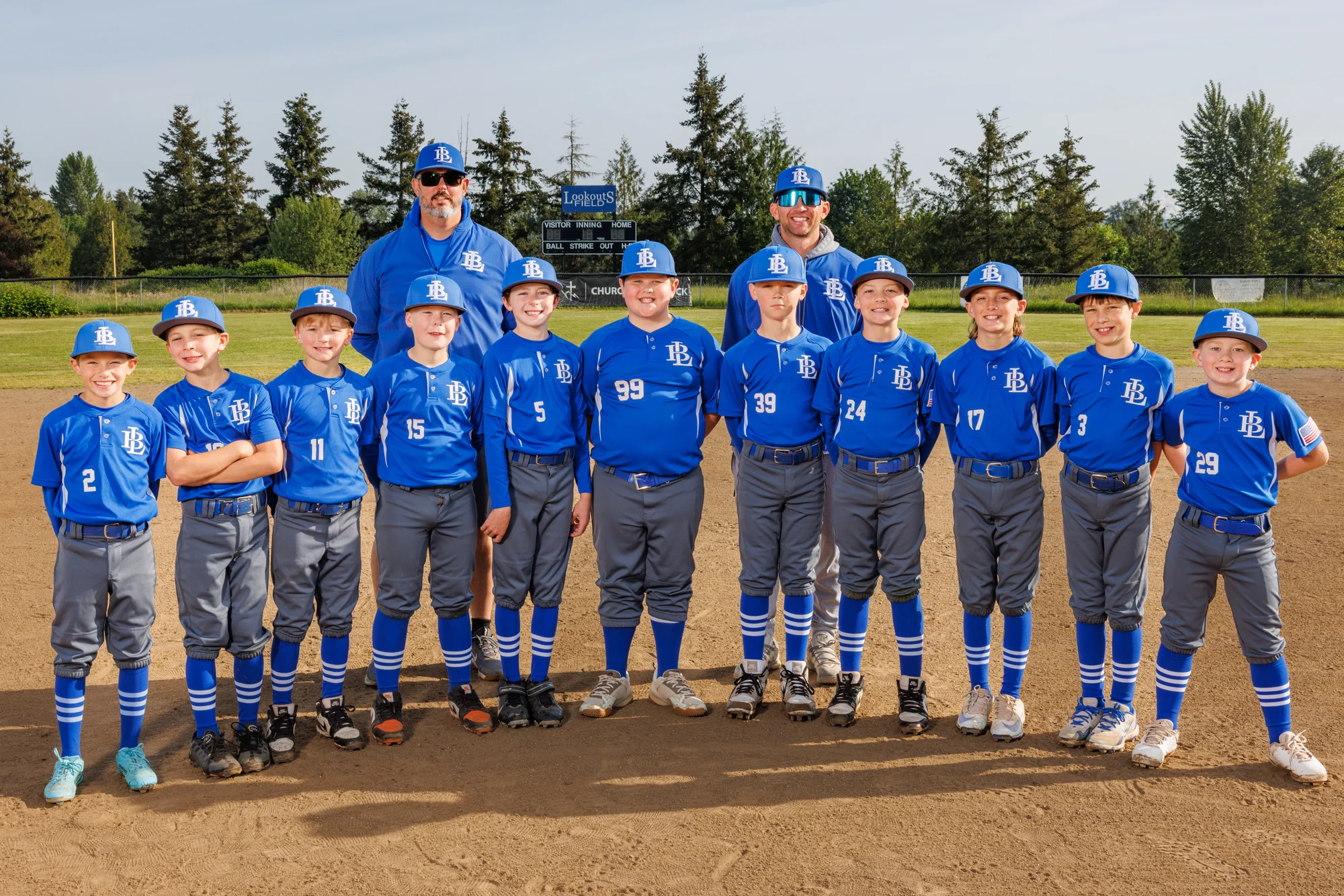 Full youth baseball team and two coaches lined up together on the infield.