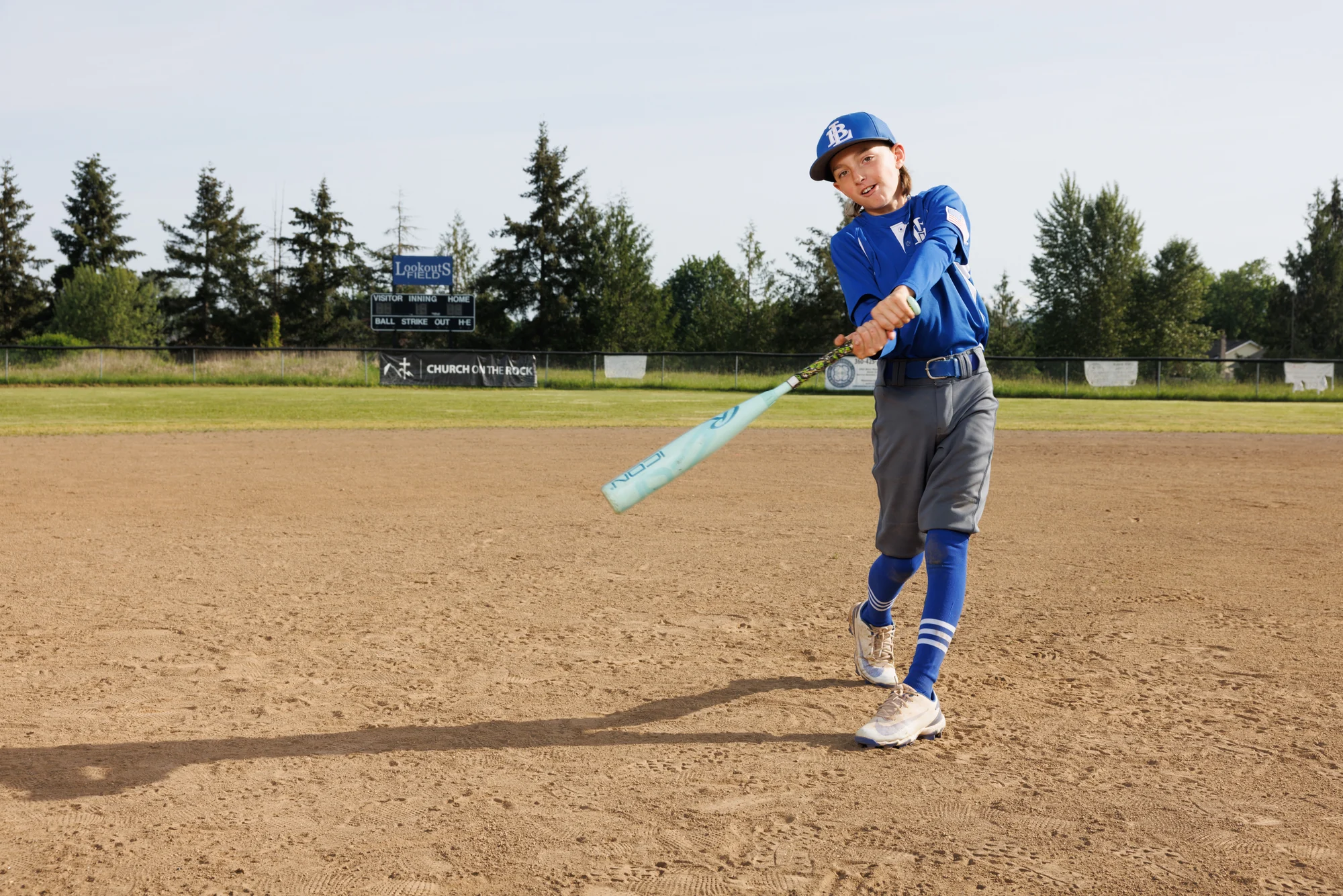 Youth baseball player completing a swing on the infield.