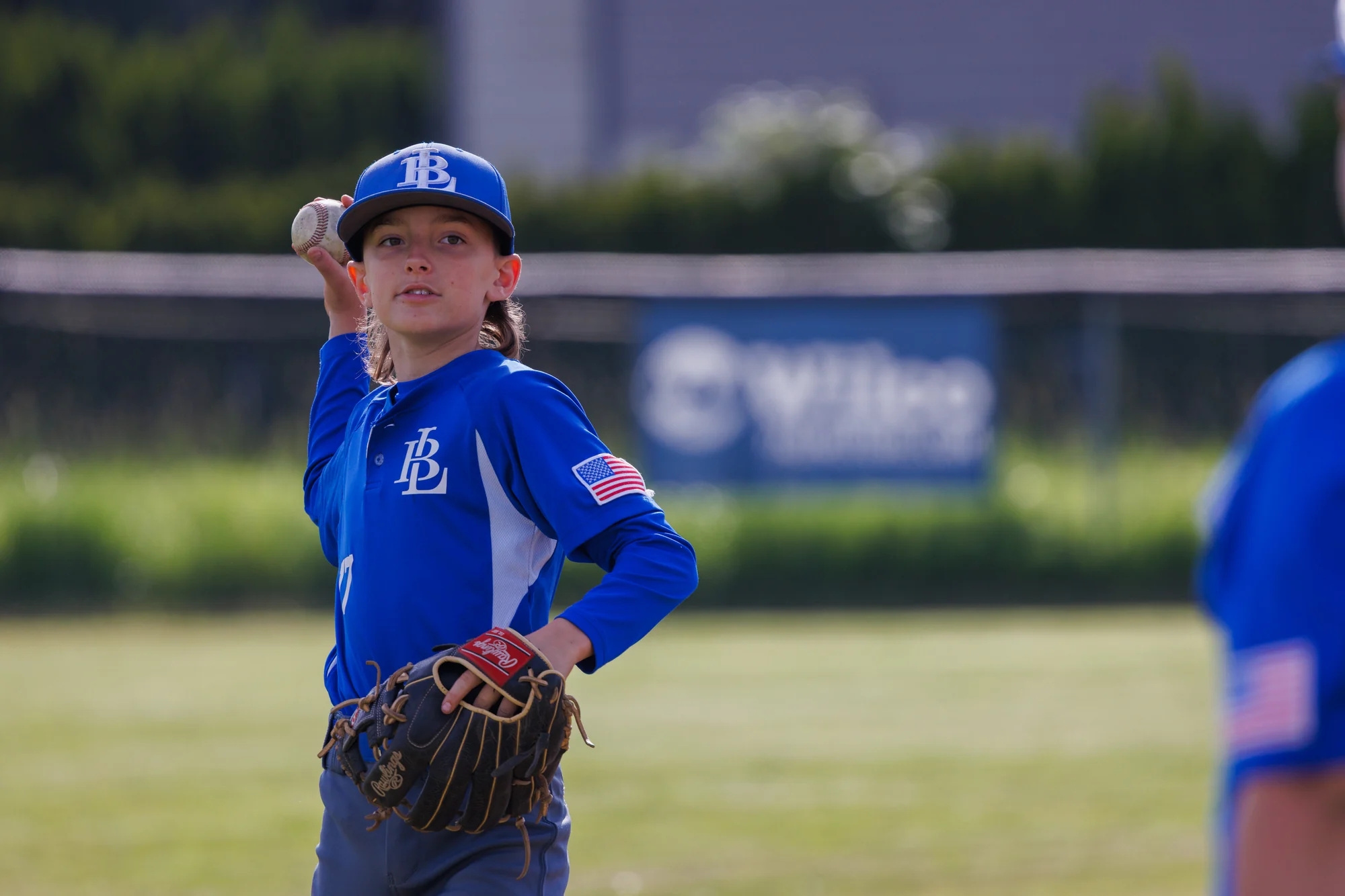 Youth baseball fielder looking upward with glove ready during warmups.