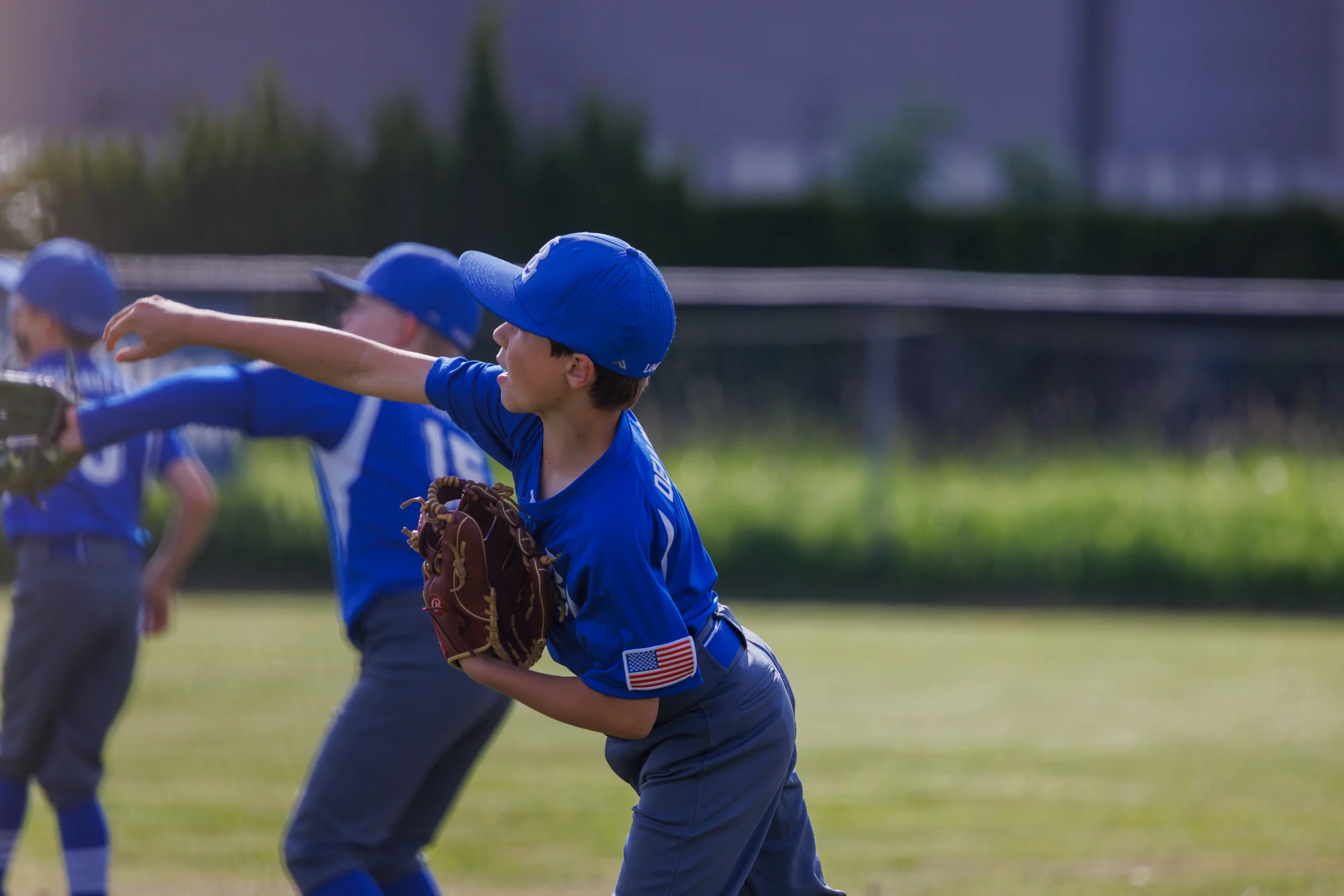 Youth baseball player beginning a throw during a fielding drill.