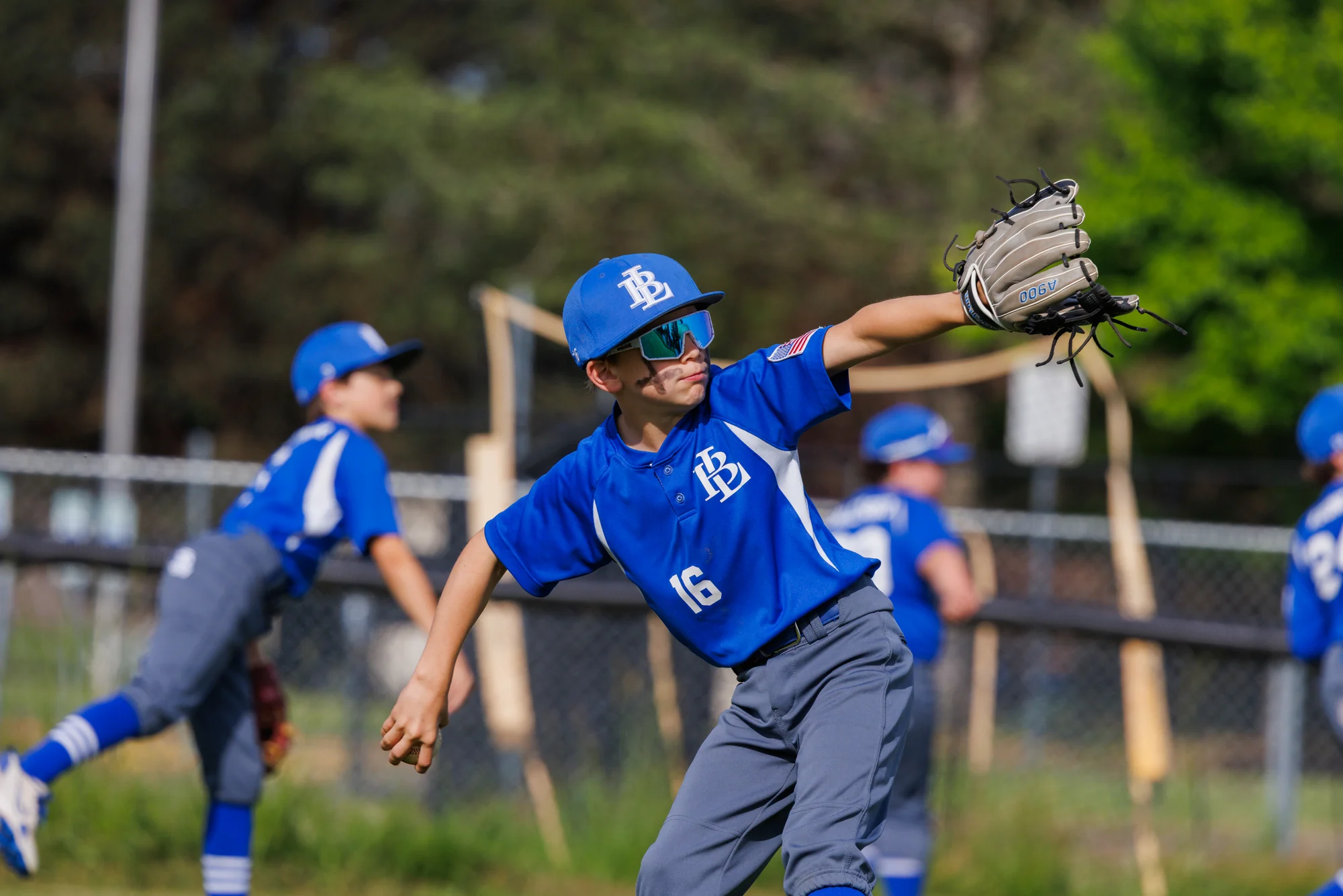 Youth baseball player delivering a throw during team warmups.