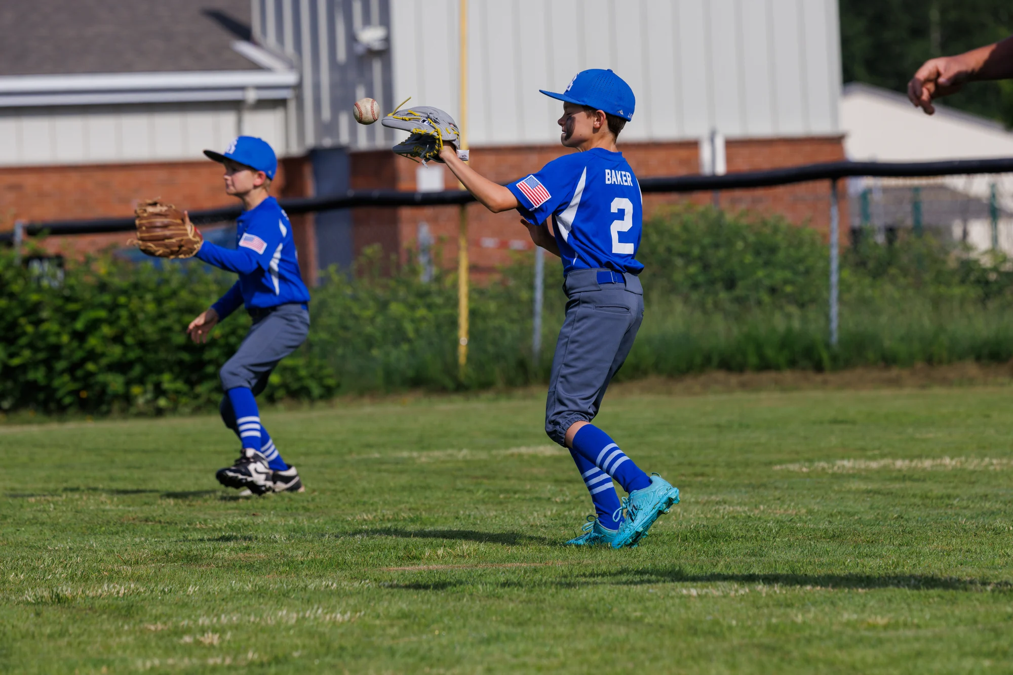Two youth baseball teammates moving through a fielding drill together.