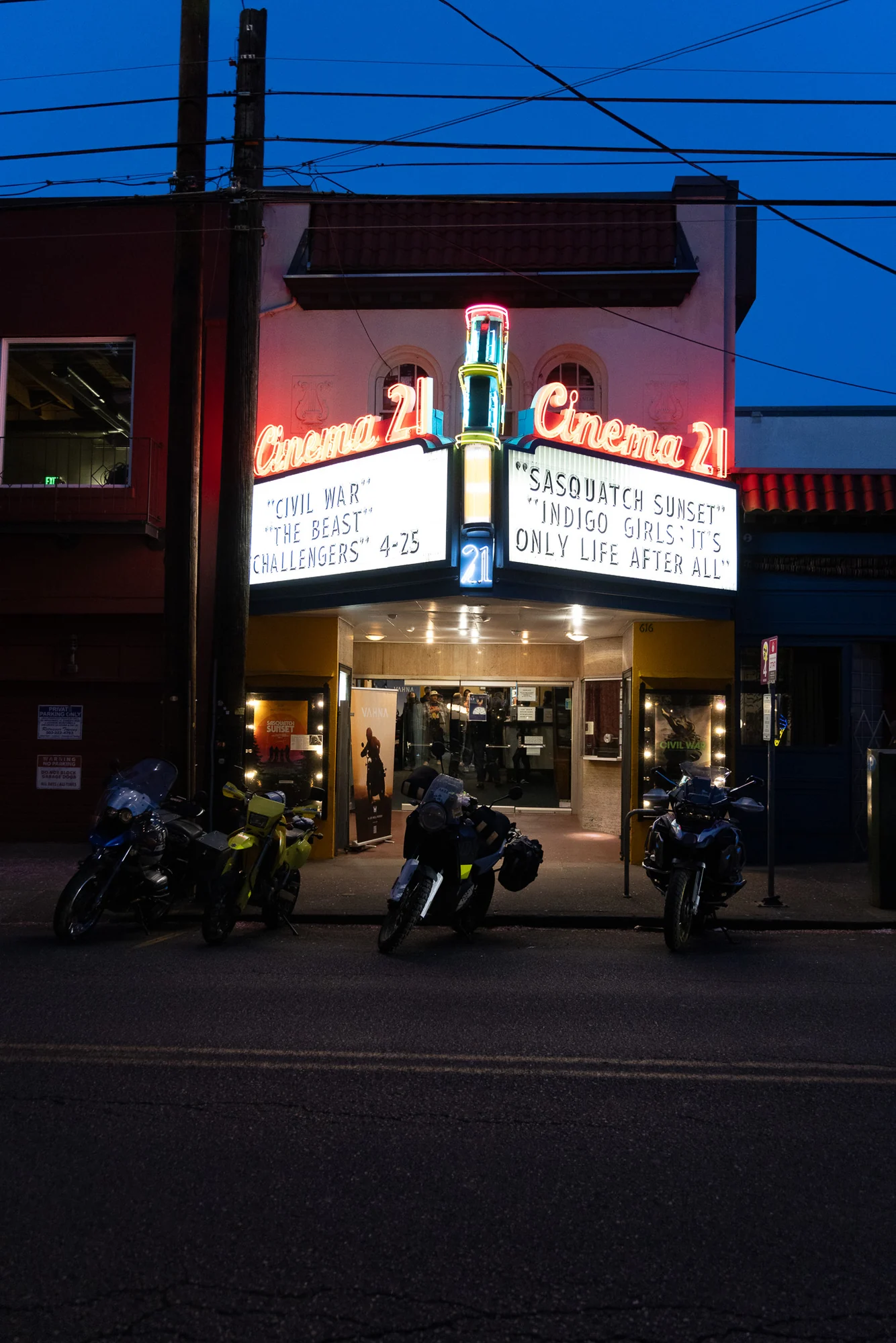 Cinema 21 and its illuminated festival marquee at twilight with motorcycles outside.