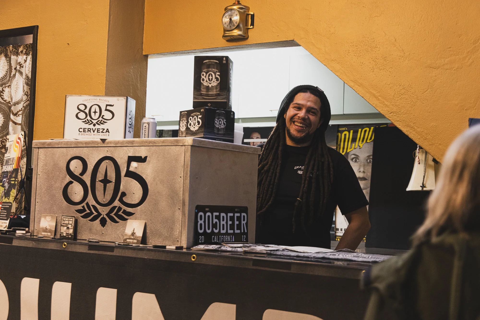 Smiling person greeting festival guests from an event partner booth.