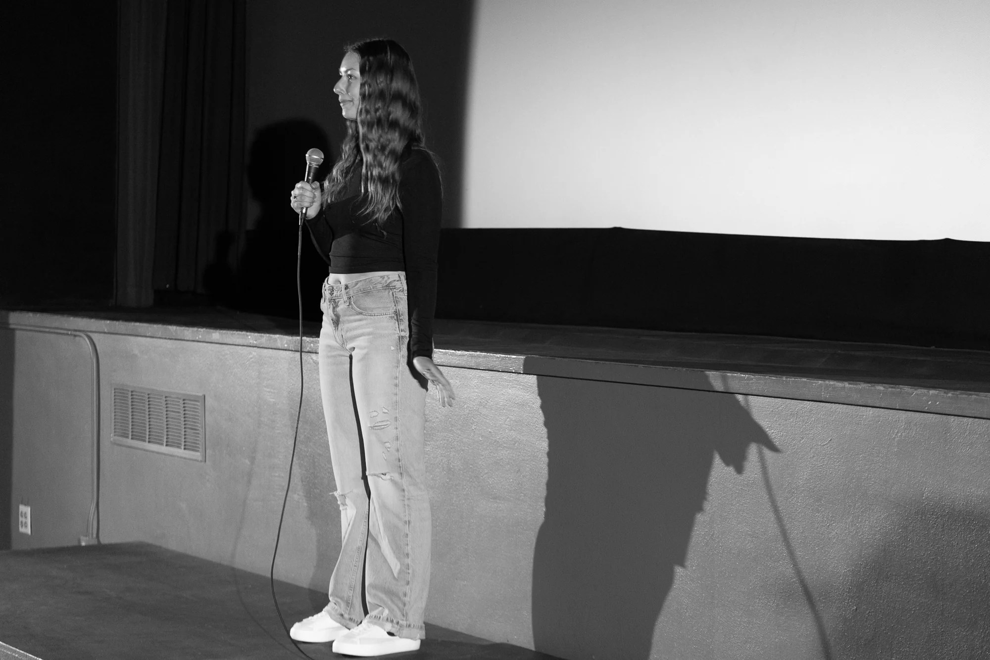 Black-and-white photograph of a festival speaker holding a microphone on stage.