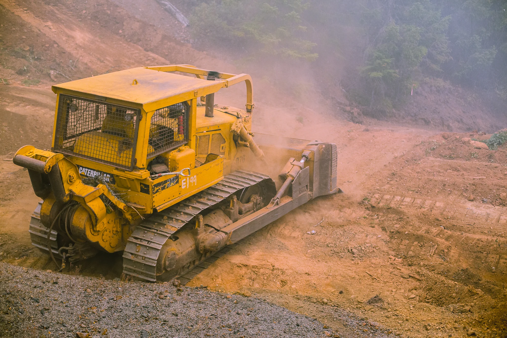 Yellow bulldozer working across a smoky dirt slope during wildfire operations.