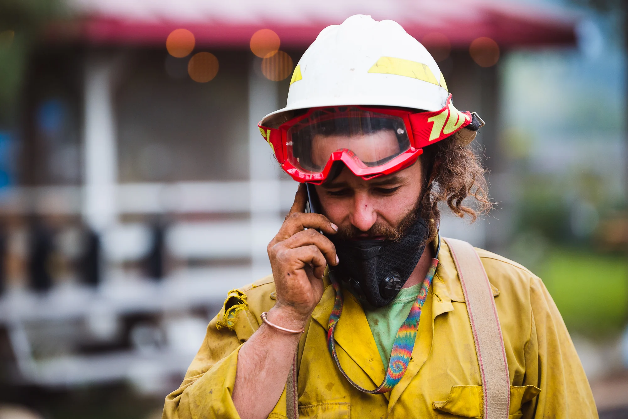 Wildland firefighter in yellow protective clothing speaking into a handheld radio.