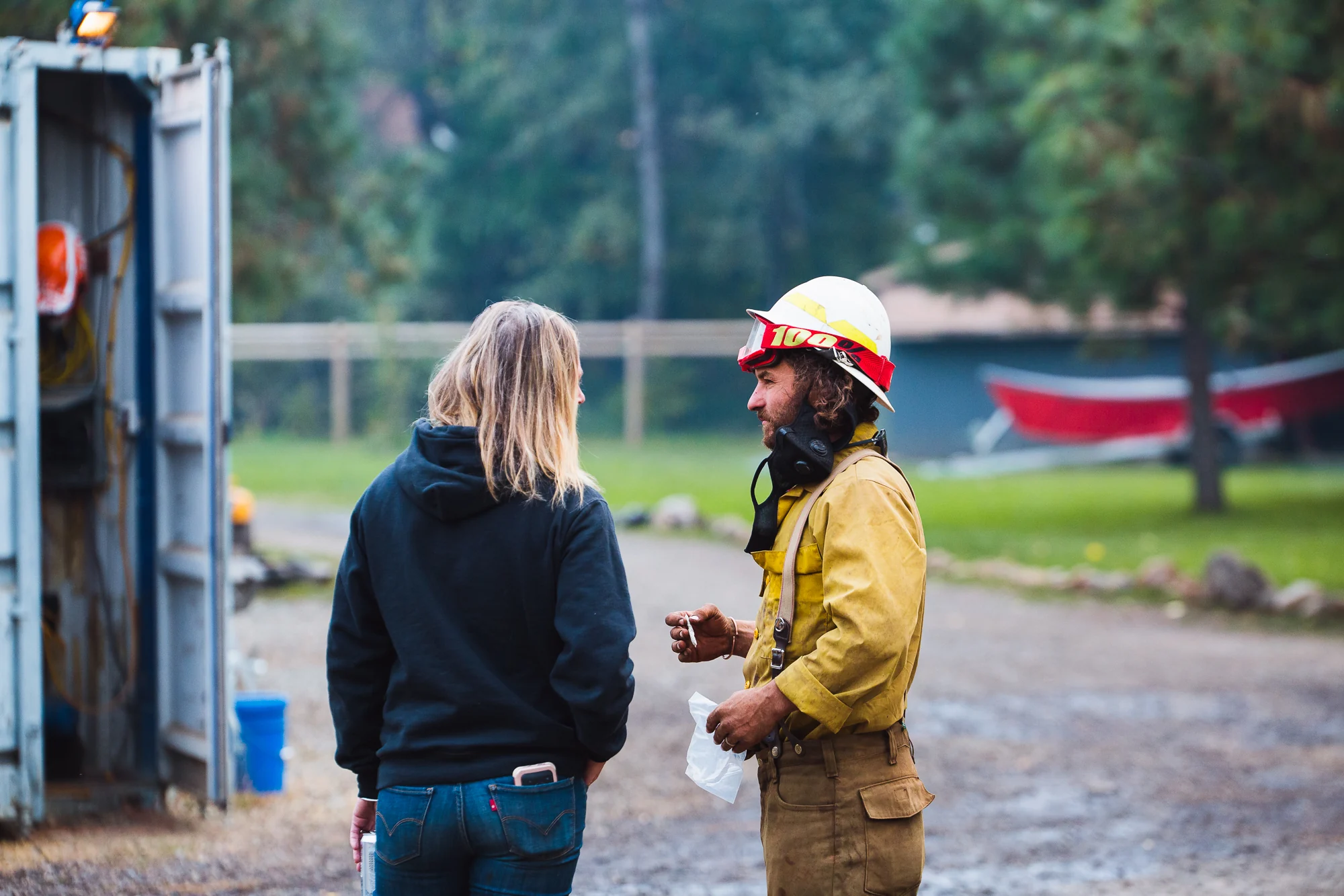 Wildland firefighter speaking with a person near field equipment and vehicles.