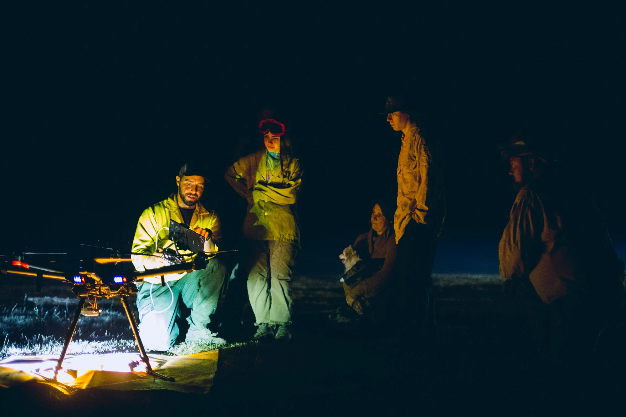 Wildland fire crew gathered around an illuminated work surface during nighttime operations.